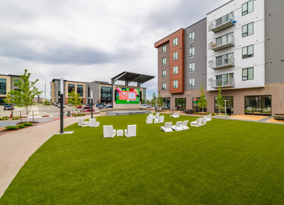 a green lawn with chairs and tables in front of an apartment building at EagleRidge Plaza Residences, North Dakota, 58104