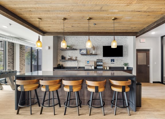 a kitchen with a large island with four stools and a tv on the wall at EagleRidge Plaza Residences, North Dakota