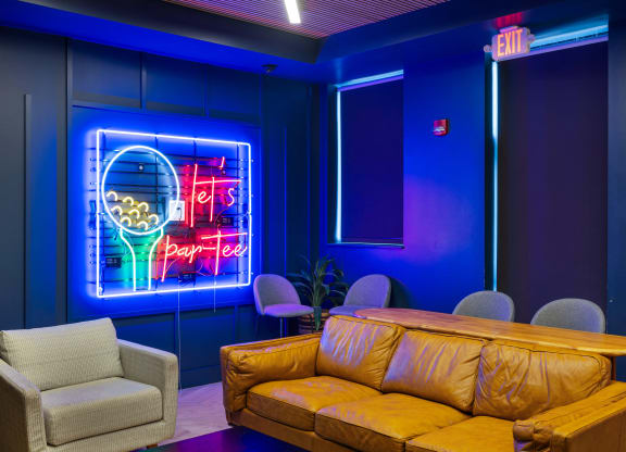 a room with a couch and chairs and a neon sign at EagleRidge Plaza Residences, Fargo, ND