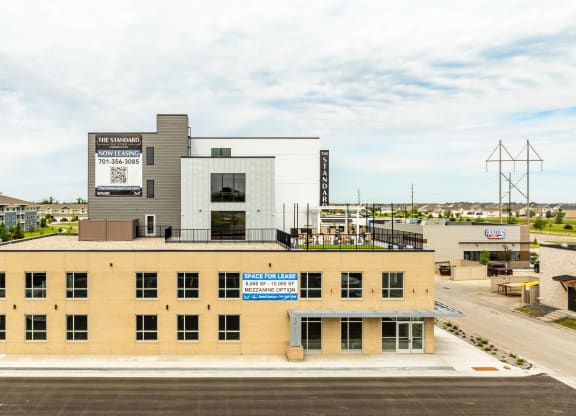 a large building with a sign on top of it in a parking lot at The Standard on 32nd, West Fargo, North Dakota