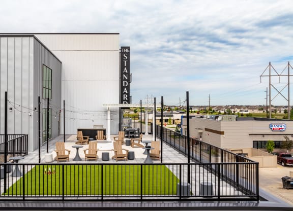 a large white building with a patio with tables and chairs at The Standard on 32nd, West Fargo