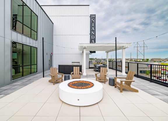 a patio with a fire pit and chairs and a building at The Standard on 32nd, West Fargo, North Dakota
