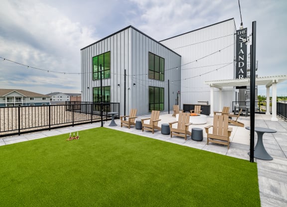 a patio with lawn chairs and a building with a sign on it at The Standard on 32nd, West Fargo, ND, 58078