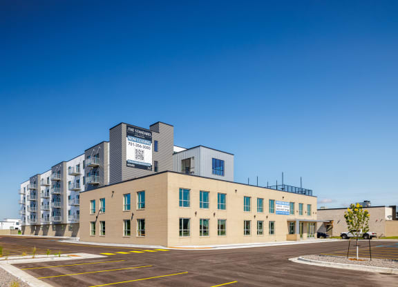 a building with a parking lot and a blue sky at The Standard on 32nd, West Fargo