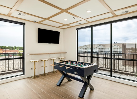 a game room with a foosball table and a large window at The Standard on 32nd, West Fargo, 58078