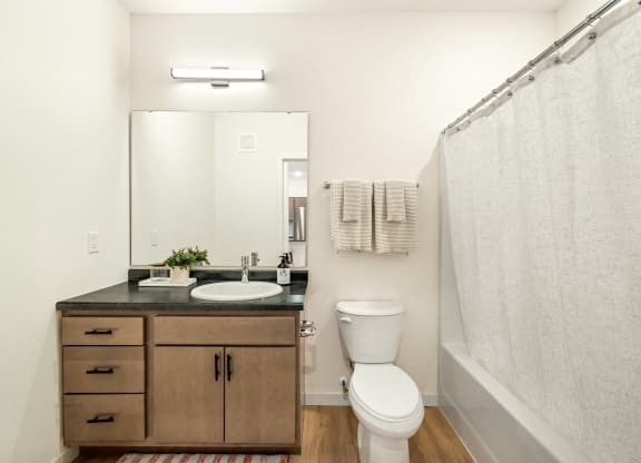 a bathroom with a toilet sink and mirror and a shower at The Standard on 32nd, West Fargo, ND