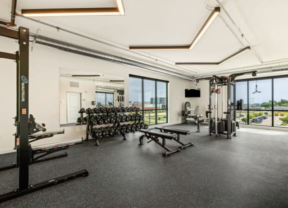a gym with weights machines and windows and a view of the city at The Standard on 32nd, West Fargo, ND, 58078