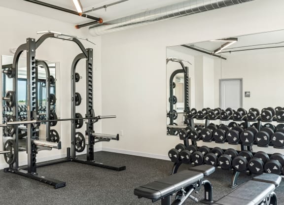 a fitness room with weights machines and mirrors at The Standard on 32nd, North Dakota, 58078