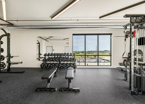 a gym with weights machines and a view of a window at The Standard on 32nd, North Dakota