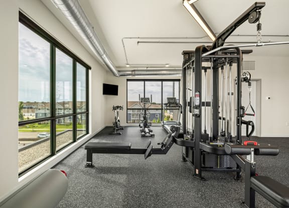 a gym with exercise equipment and windows with a view of a train at The Standard on 32nd, West Fargo, 58078