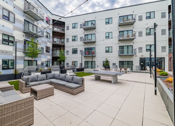 an open courtyard with couches and tables in front of an apartment building Northern Lights a Lifestyle-Driven Community, West Fargo, 58078