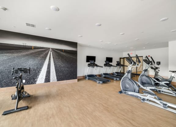 a gym with treadmills and dumbbells on a wood floor at Northern Lights a Lifestyle-Driven Community, West Fargo, North Dakota