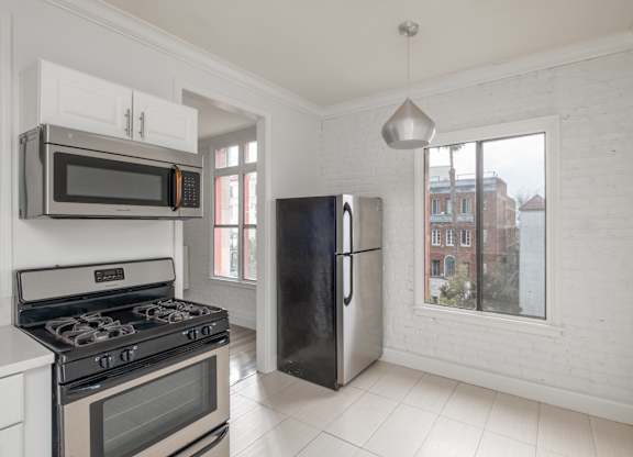 A kitchen with a black refrigerator and a black stove top oven at Mariposa Willows Apartments, Los Angeles
