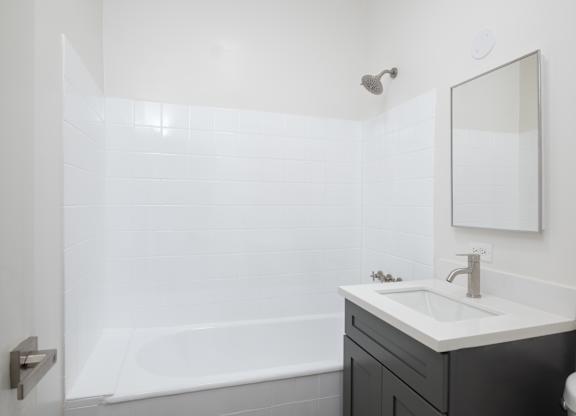 A white bathroom with a black vanity and a white tub at Westmore Manor Apartments, Los Angeles, California