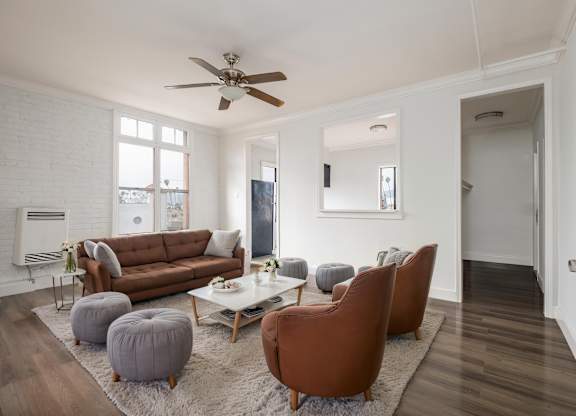 A living room with a brown couch, two chairs, and a coffee table at Mariposa Willows Apartments, Los Angeles, 90004