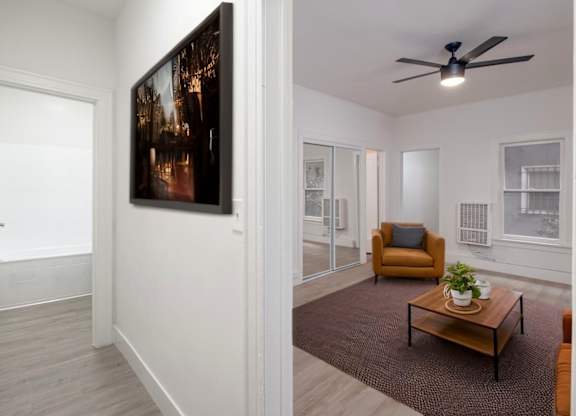 A living room with a brown armchair, a coffee table, and a painting on the wall at Westmore Manor Apartments, California