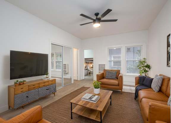 A living room with a brown sofa, a wooden coffee table, and a flat-screen TV at Westmore Manor Apartments, California, 90020