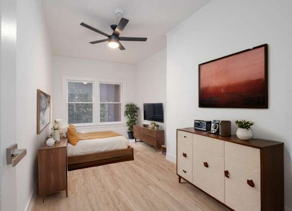 A bedroom with a bed, dresser, and a ceiling fan at Westmore Manor Apartments, Los Angeles