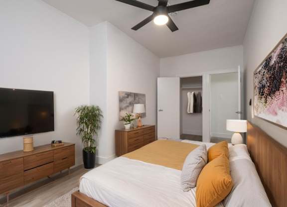A bedroom with a bed, a television, and a ceiling fan at Westmore Manor Apartments, Los Angeles, CA