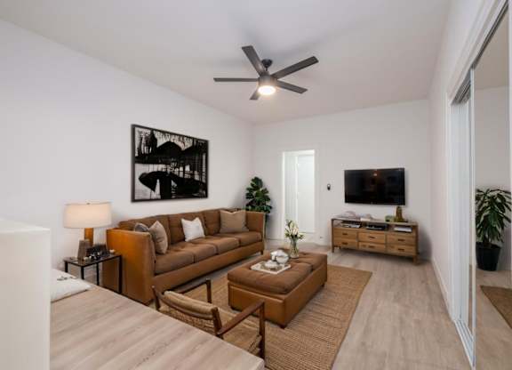 A living room with a brown couch and a ceiling fan at Westmore Manor Apartments, Los Angeles, 90020