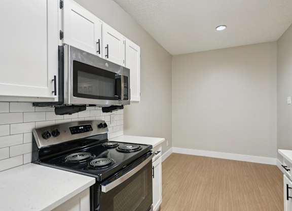 A kitchen with a stove, microwave, and cabinets.