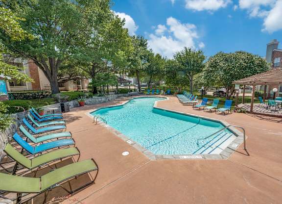 a resort style swimming pool with lounge chairs and umbrellas at Foxborough Apartments, Irving, TX, Texas, 75061