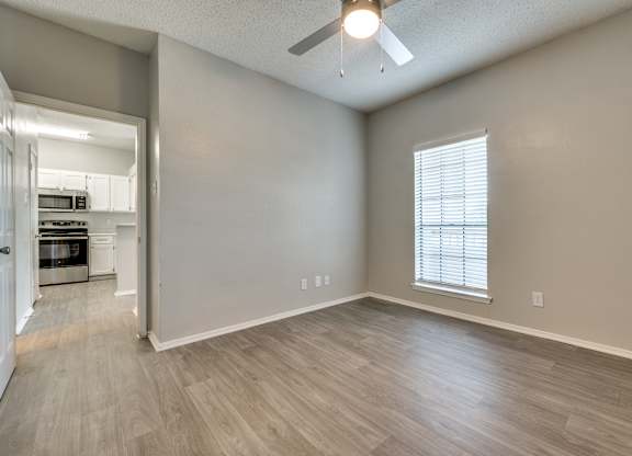 an empty living room with a ceiling fan and a kitchen at Foxborough Apartments, Irving, TX, Texas, 75061