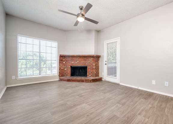 an empty living room with a fireplace and a ceiling fan at Foxborough Apartments, Irving, TX, Texas, 75061