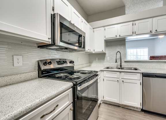 an empty kitchen with white cabinets and a stove and microwave at Foxborough Apartments, Irving, TX, Texas, 75061