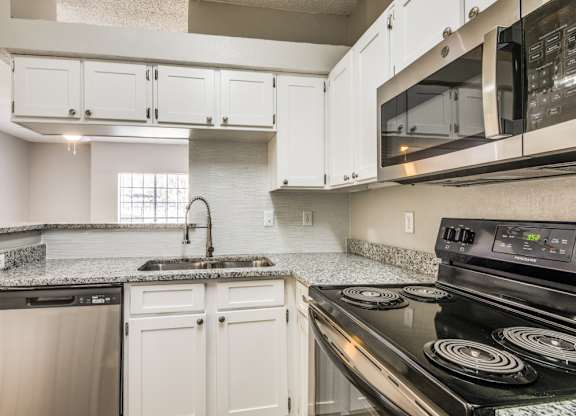 a kitchen with white cabinets and black appliances at Foxborough Apartments, Irving, TX, 75061
