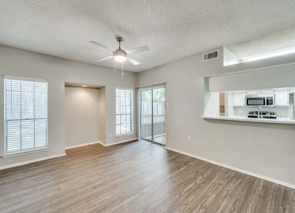 an empty living room with a ceiling fan and a kitchen at Foxborough Apartments, Irving, TX, Texas, 75061