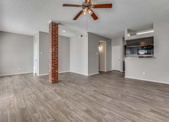 an empty living room with a ceiling fan and a kitchen at Foxborough Apartments, Irving, TX, Texas, 75061