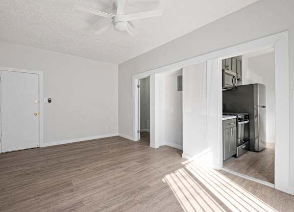 A room with a ceiling fan and a kitchen area in the background at Hillstone Flats Apartments, Los Angeles, CA