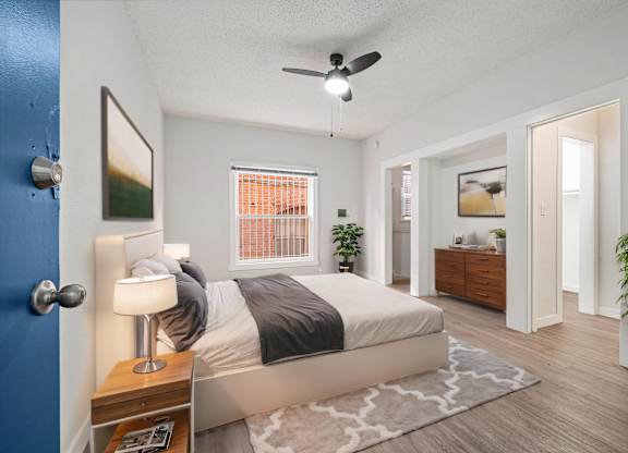 A bedroom with a bed, nightstand, and a plant at Hillstone Flats Apartments, Los Angeles, CA