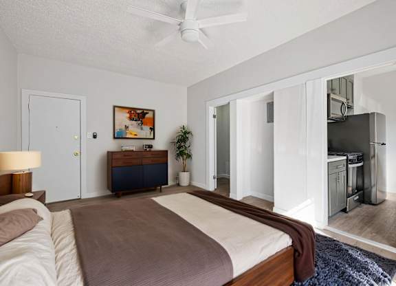 A bedroom with a bed, dresser, and a ceiling fan at Hillstone Flats Apartments, Los Angeles, CA