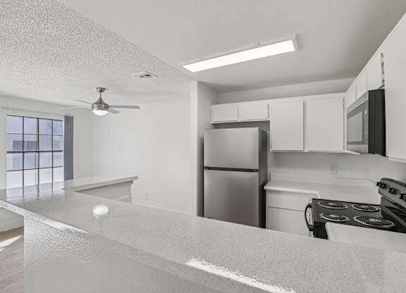 A kitchen with a refrigerator, stove, and microwave.
