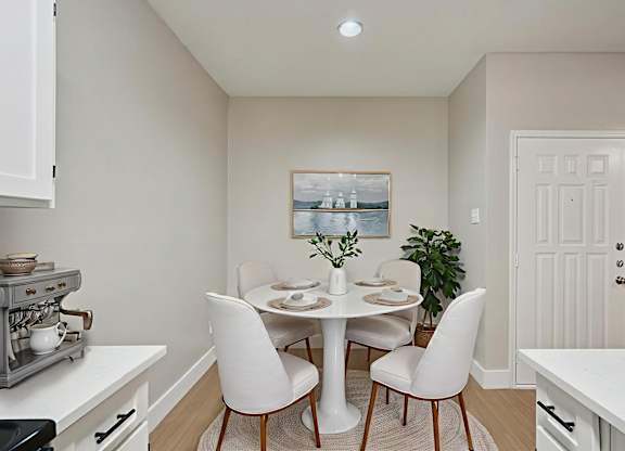 A dining room with a white table and chairs.