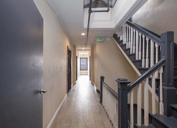 A long hallway with a staircase on the right and a door on the left at Mariposa Willows Apartments, Los Angeles, California