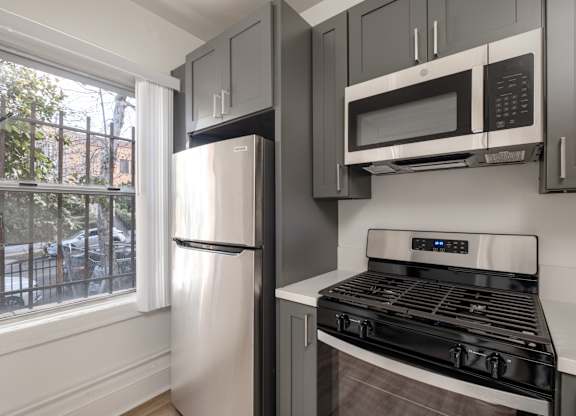 A kitchen with a stove, refrigerator, and microwave at Kenmore Park Apartments, Los Angeles, CA