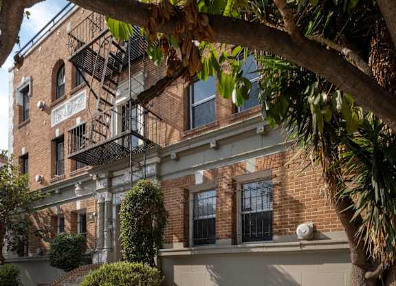 A tree is in front of a building with a sign at Kenmore Park Apartments, Los Angeles, 90004