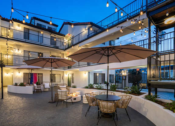 a patio with tables and chairs and umbrellas at night