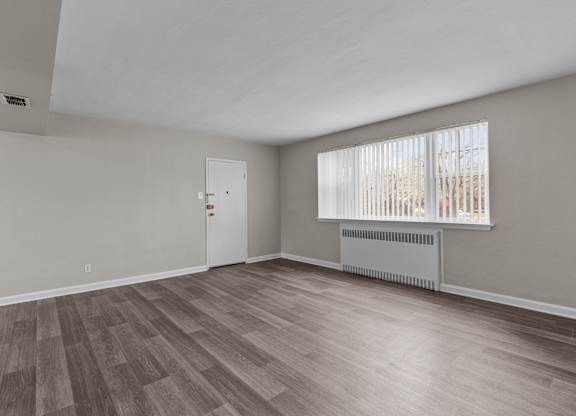 the living room of an empty house with wood flooring and a window at Hampton Gardens, Missouri, 63139