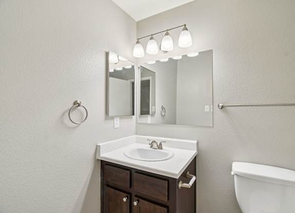 A bathroom with a sink, mirror, and toilet.