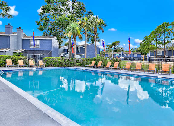 A swimming pool in front of a house with palm trees.