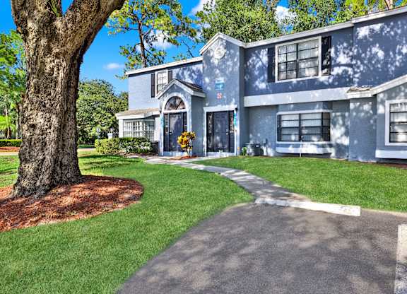A blue house with a tree in front.