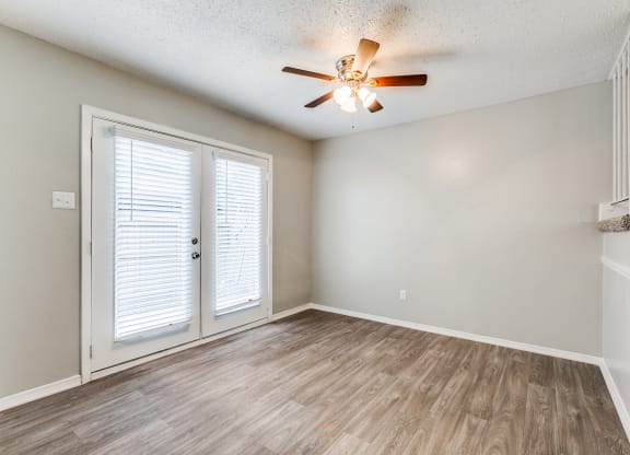 an empty living room with a ceiling fan and a door at Falls on Clearwood Apartments, Richardson, TX, Texas