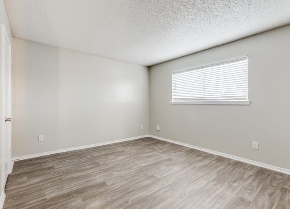 the spacious living room with wood flooring and a window at Falls on Clearwood Apartments, Richardson, TX, Texas