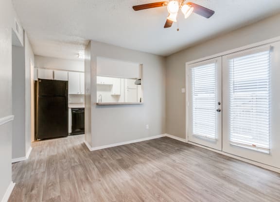 an empty living room with a kitchen and a ceiling fan at Falls on Clearwood Apartments, Richardson, TX, Texas