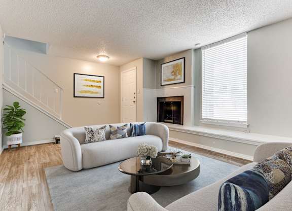 a living room with a couch and a table in front of a fireplace at Falls on Clearwood Apartments, Richardson, TX, Texas