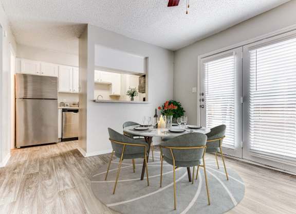 a dining room with a table and chairs and a kitchen with stainless steel appliances at Falls on Clearwood Apartments, Richardson, TX, Texas